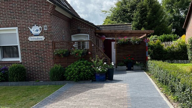 Une maison en briques avec un sentier de jardin menant à une pergola en bois.