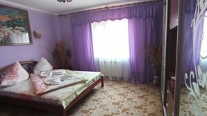 Un dormitorio con cama, cortinas moradas, una ventana y un cuadro en la pared.