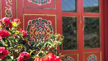 Um edifício vermelho com desenhos decorativos e um arbusto de flores em primeiro plano.