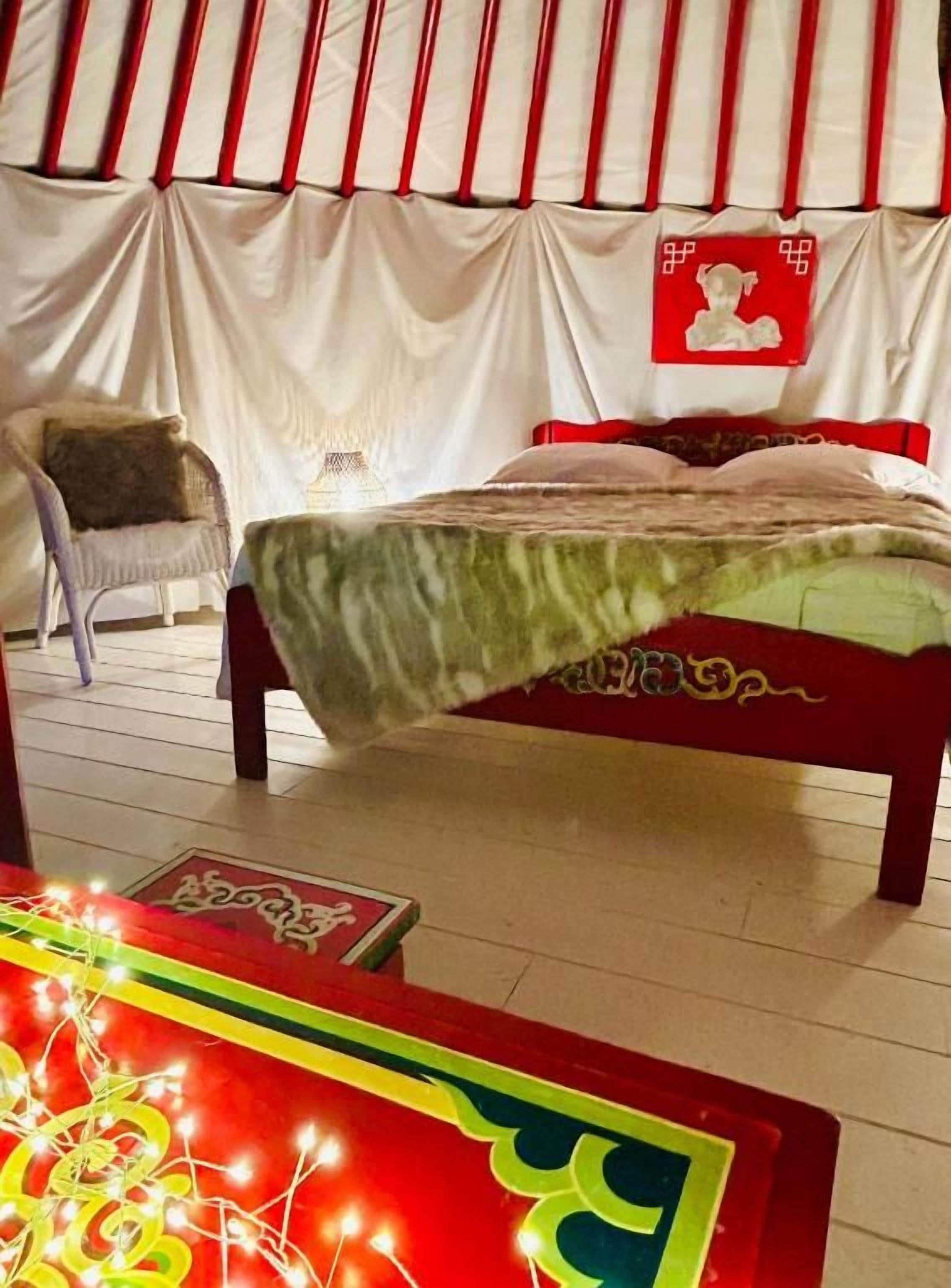A bed with a green bedspread, a chair, and a wall with a red and white striped pattern.
