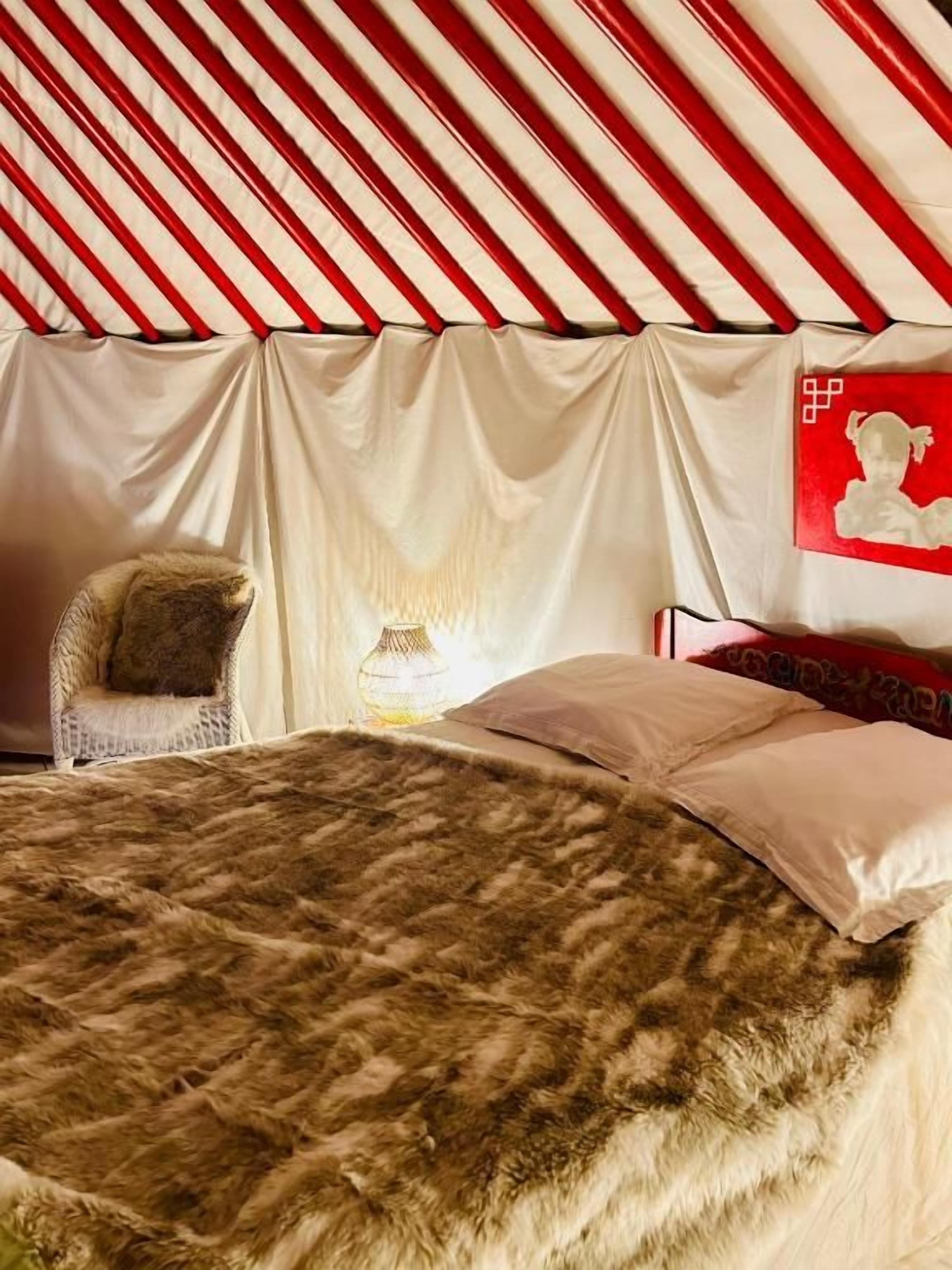 Ein Zelt mit einem Bett, einem Stuhl und einer Lampe.