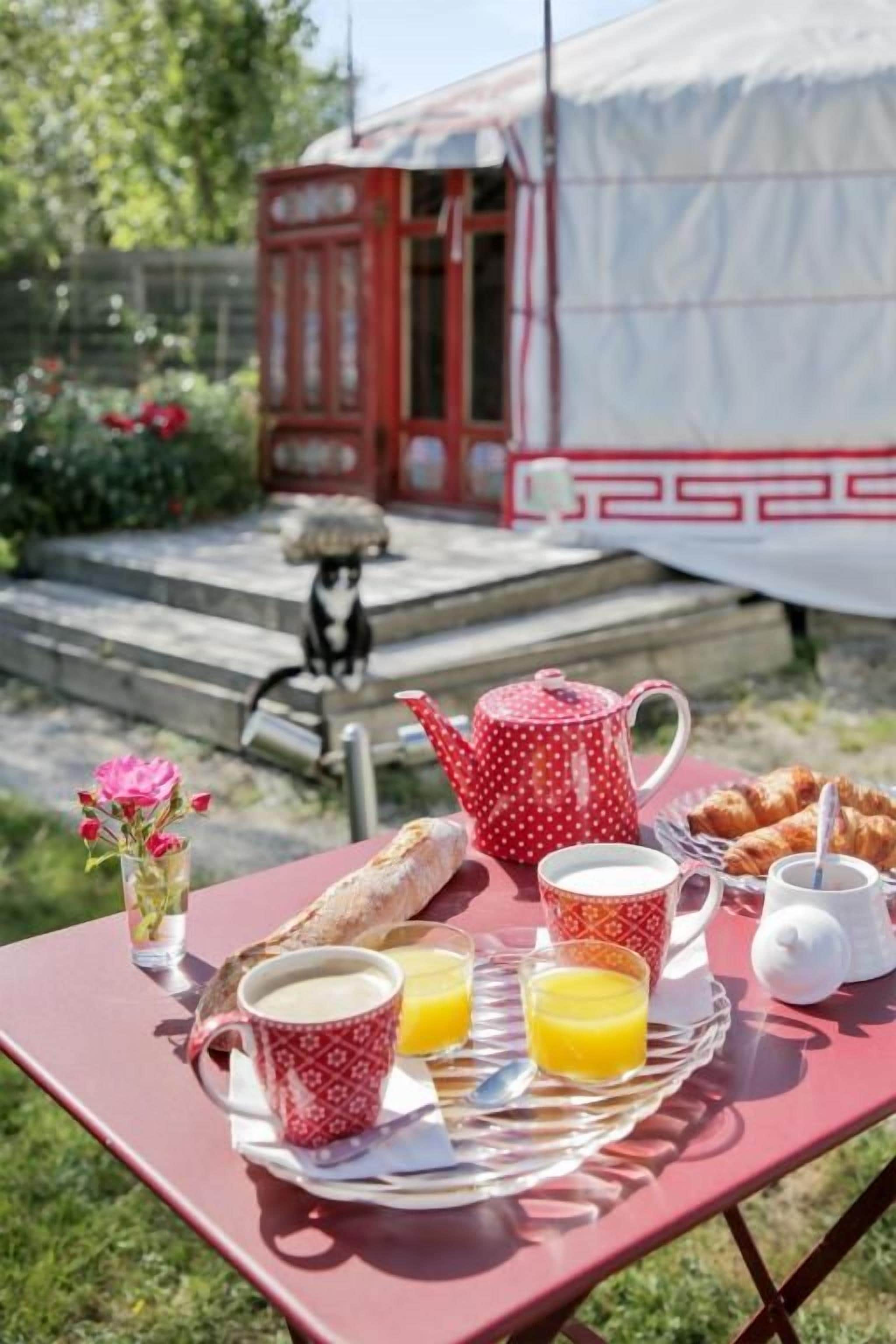 A picnic setup with a tray of food, a teapot, cups, and a small table.