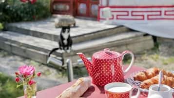 A picnic setup with a tray of food, a teapot, cups, and a small table.