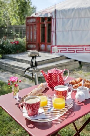 A picnic setup with a tray of food, a teapot, cups, and a small table. - Yourte au Paradis (Souvigné)
