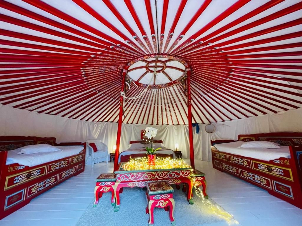 Une pièce aménagée comme une tente, avec deux lits, une table centrale dotée de lampes et un auvent décoratif.