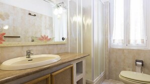 A bathroom with a sink, mirror, shower, toilet, and a window. - Belmare (Porto Azzurro)