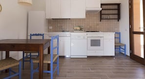 A kitchen with white cabinets, a wooden table, and blue chairs.