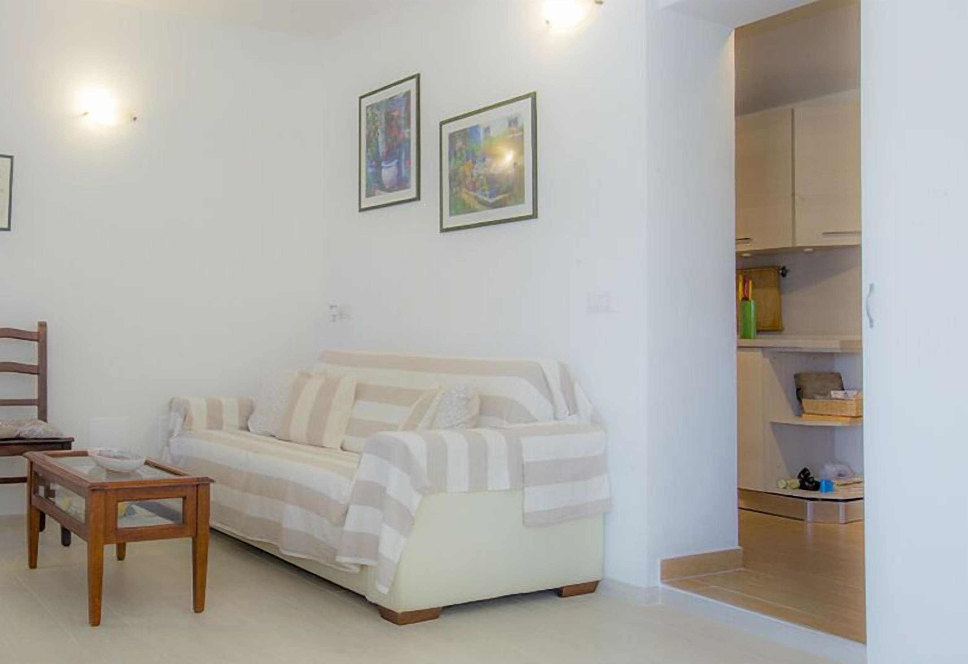 A living room with a sofa, a wooden coffee table, and two framed artworks on the wall.