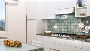 Een keuken met uitzicht op bergen, een fornuis en een eettafel met een bloemenboeket.