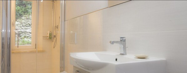 Une salle de bain avec un lavabo blanc, un miroir et une douche.