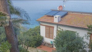 Een huis aan de kust met een pannendak, een schotelantenne en uitzicht op zee.