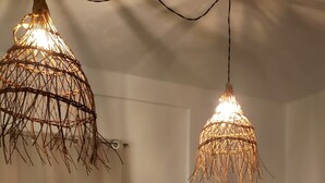 Un comedor con una mesa de madera, sillas amarillas y dos lámparas colgantes de fibra.