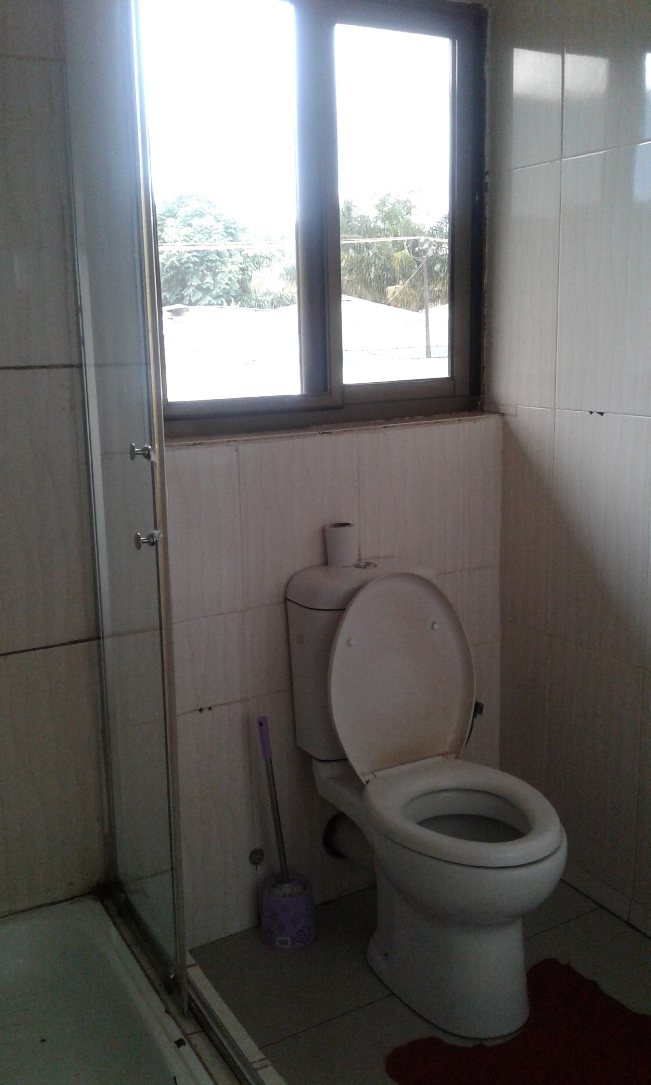 Un baño pequeño con inodoro, ventana y zona de ducha.