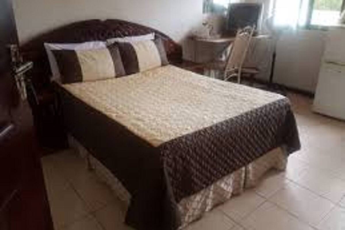 A bedroom with a bed, a desk, and a chair.