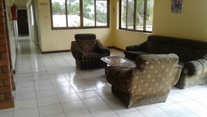 Un hall d’entrée avec un sol carrelé, deux fauteuils, un canapé et une table basse.