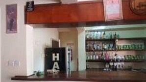 Un espace bar doté d’un comptoir en bois et d’étagères remplies de bouteilles.