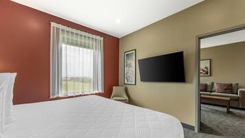 A hotel room with a large bed, a television mounted on the wall, and a chair.