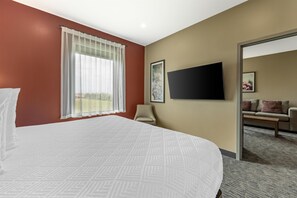 A hotel room with a large bed, a television mounted on the wall, and a chair.