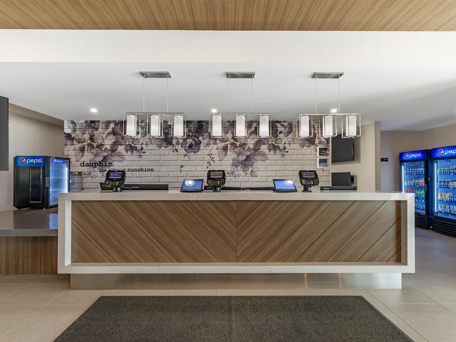 A modern reception desk with a wooden finish, multiple Lenovo computers, and a floral-patterned wall behind.