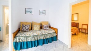 Een slaapkamer met een bed, een houten hoofdbord, een stoel en een nachtkastje met een lamp.