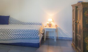 A bedroom with a bed, a nightstand with a lamp, and a wooden cabinet.