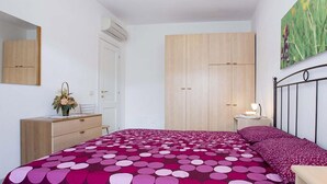A bedroom with a bed, dresser, wardrobe, and bedside table.