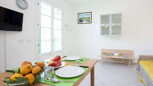 A dining area with a table set for two, a bench, and a TV mounted on the wall.