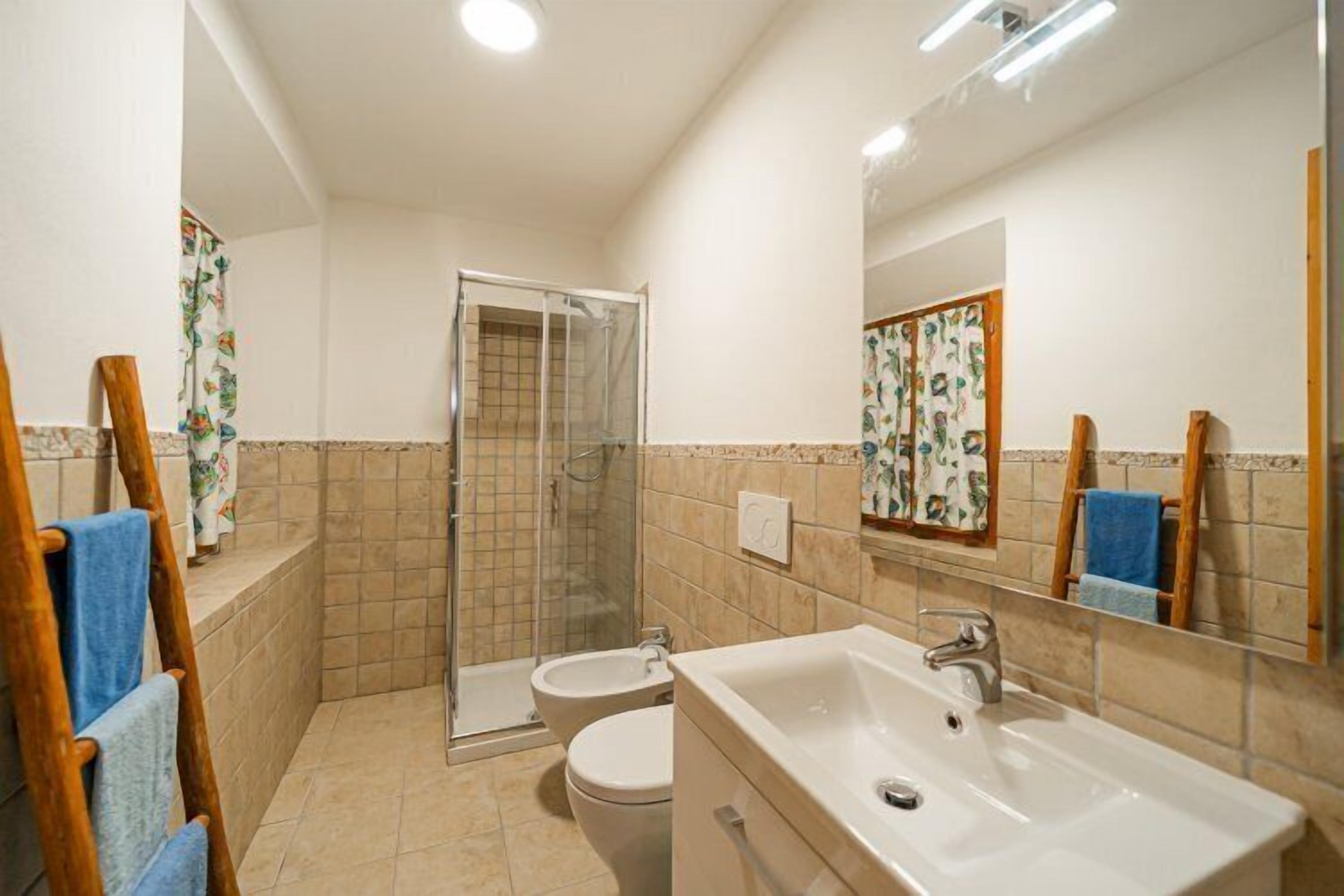 Een badkamer met douche, toilet en wastafel.