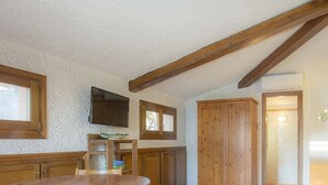 A room with wooden beams, a television, a wooden cabinet, and a framed picture on the wall. - Mansarda il Sarago (Campo nell'Elba)