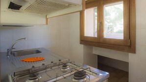 A kitchen with a gas stove, sink, and window. - Mansarda il Sarago (Campo nell'Elba)