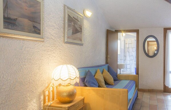 A cozy room with a bed, a lamp, and two framed pictures on the wall.