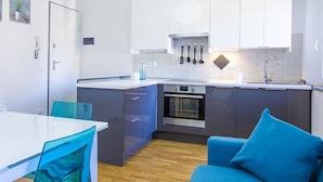 Una cocina moderna con armarios grises, encimera blanca y una silla azul.