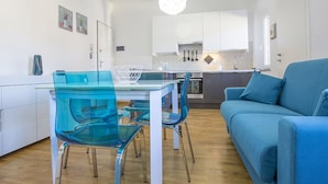 Una cocina moderna con armarios blancos y una mesa de comedor azul con sillas transparentes.