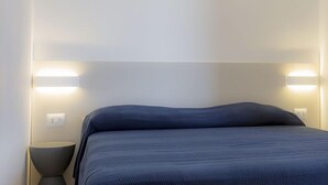 A modern bedroom with a large bed, two bedside lamps, and a neutral color scheme. - Punta dei Barbari (Rio)