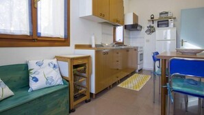 A compact kitchen with wooden cabinets, a microwave, and a small refrigerator. - Santa Petronilla (Capoliveri)