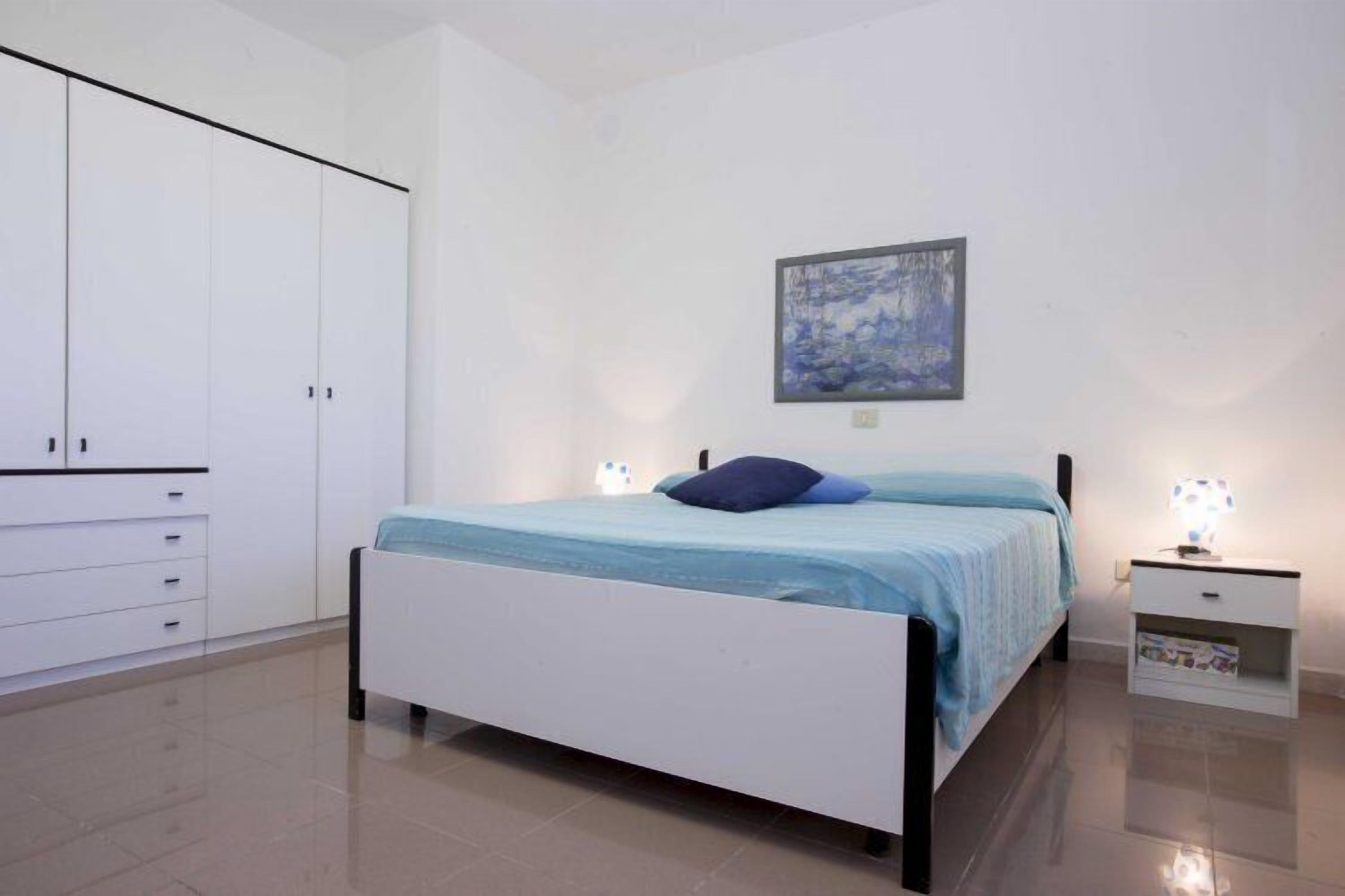 Une chambre à coucher avec un lit, une table de chevet, une armoire et un tableau au mur.