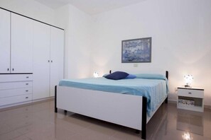 A bedroom with a bed, a nightstand, a wardrobe, and a painting on the wall.
