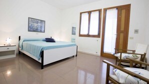 A bedroom with a bed, bedside table, and a chair. - Santa Petronilla (Capoliveri)