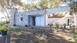 A modern house with a stone facade, a circular window, and a small garden with potted plants. - Villa Meridiana (Portoferraio)