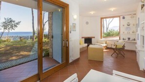 A spacious living area with a sliding glass door leading to a balcony overlooking a scenic landscape. - Villa Meridiana (Portoferraio)