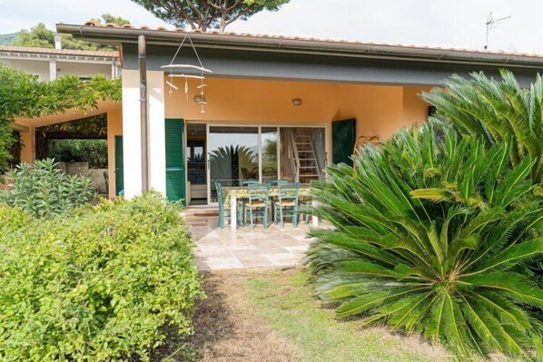 Une maison avec un patio, des volets verts et une table avec des chaises.