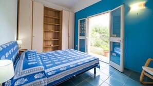 Un dormitorio con una cama, un armario, una mesita pequeña y una silla.