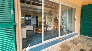 Una casa moderna con un puerta de vidrio que da a una sala de estar con sofá, mesa de centro y sillas.