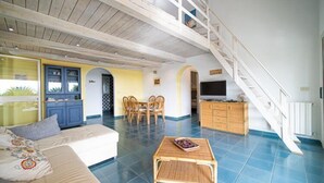 Amplia sala de estar con sofá, mesa de comedor y escalera que lleva a un nivel superior.