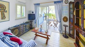 Un salon comprenant un canapé, une table basse, un téléviseur et un coin repas avec une table et des chaises.