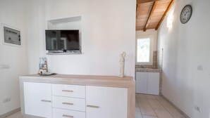 Eine moderne Küche mit integriertem Fernseher, weißen Schränken und einer Holzarbeitsplatte.