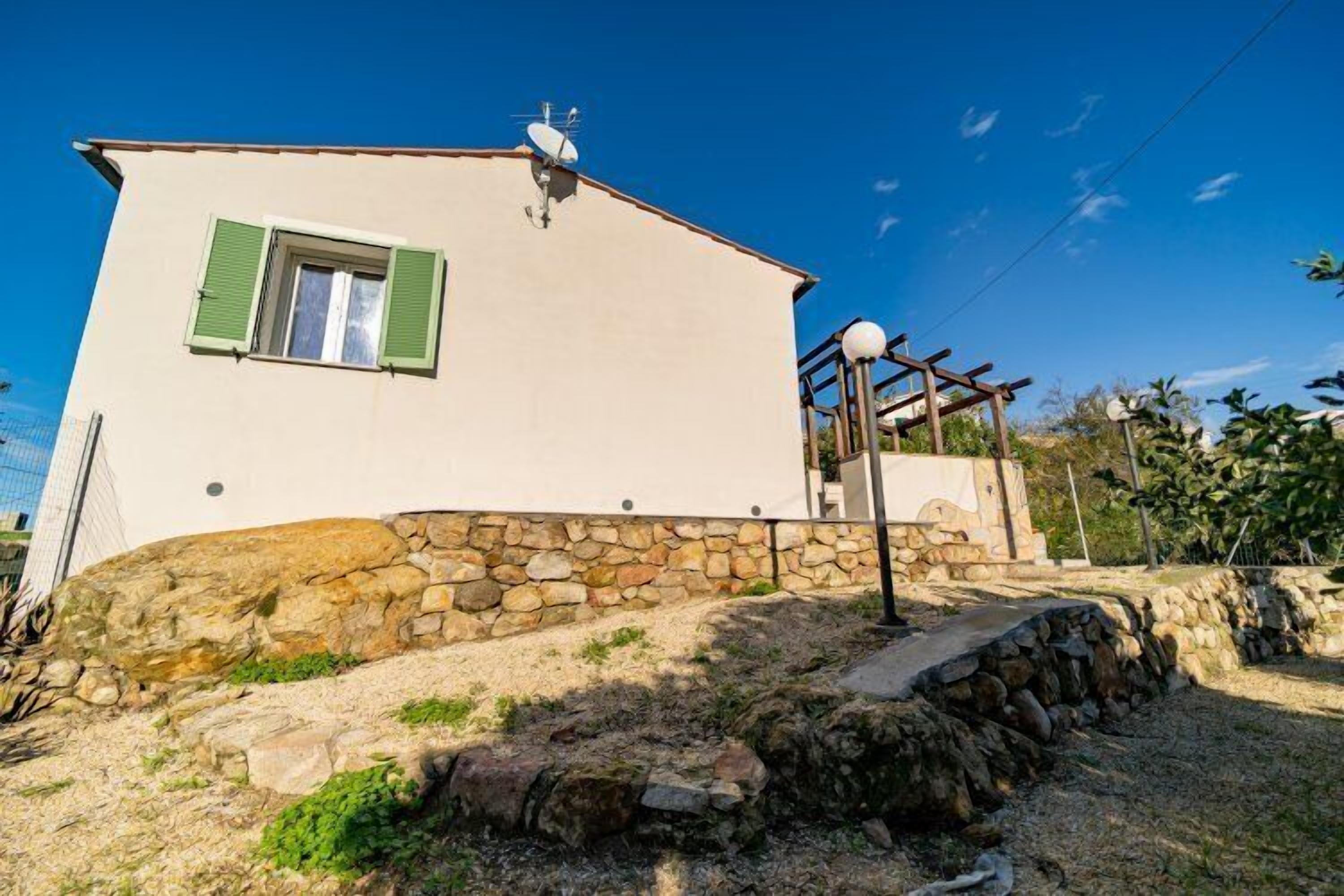 A two-story building with a stone foundation, a satellite dish, and a pergola.