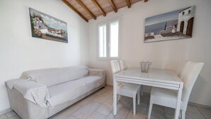 Ein Zimmer mit einer Couch, einem Esstisch mit Stühlen und zwei Bildern an den Wänden.