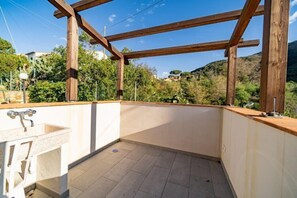 A balcony with a wooden pergola, a sink, and a view of a mountainous landscape. - Villetta La Zanca (Marciana)