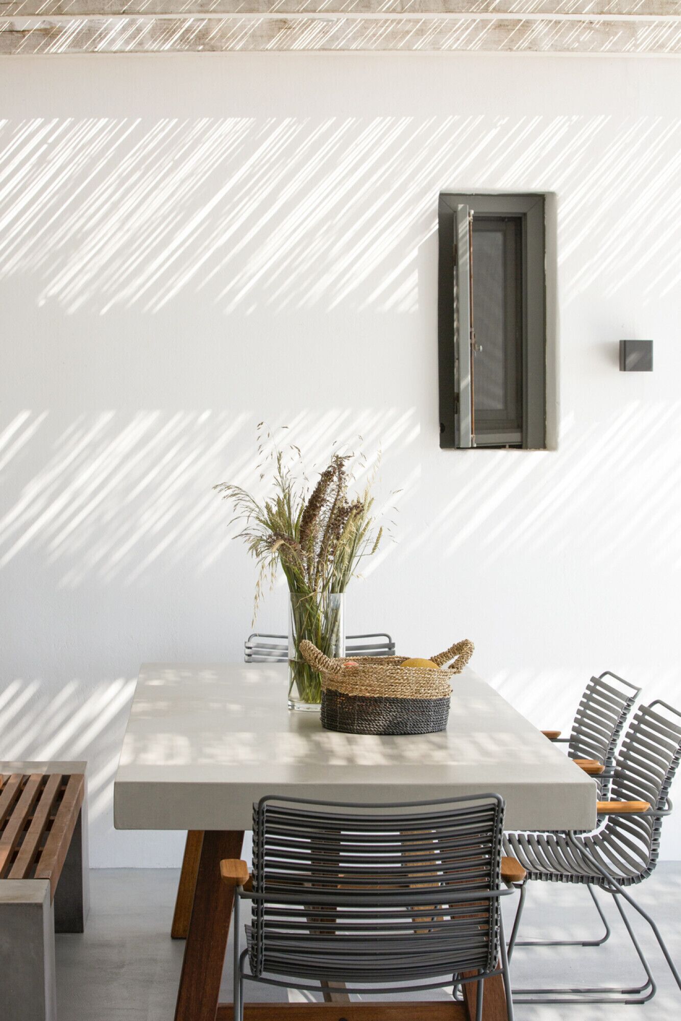 Un comedor con una mesa rectangular, un centro de mesa de cesta tejida y sillas metálicas.